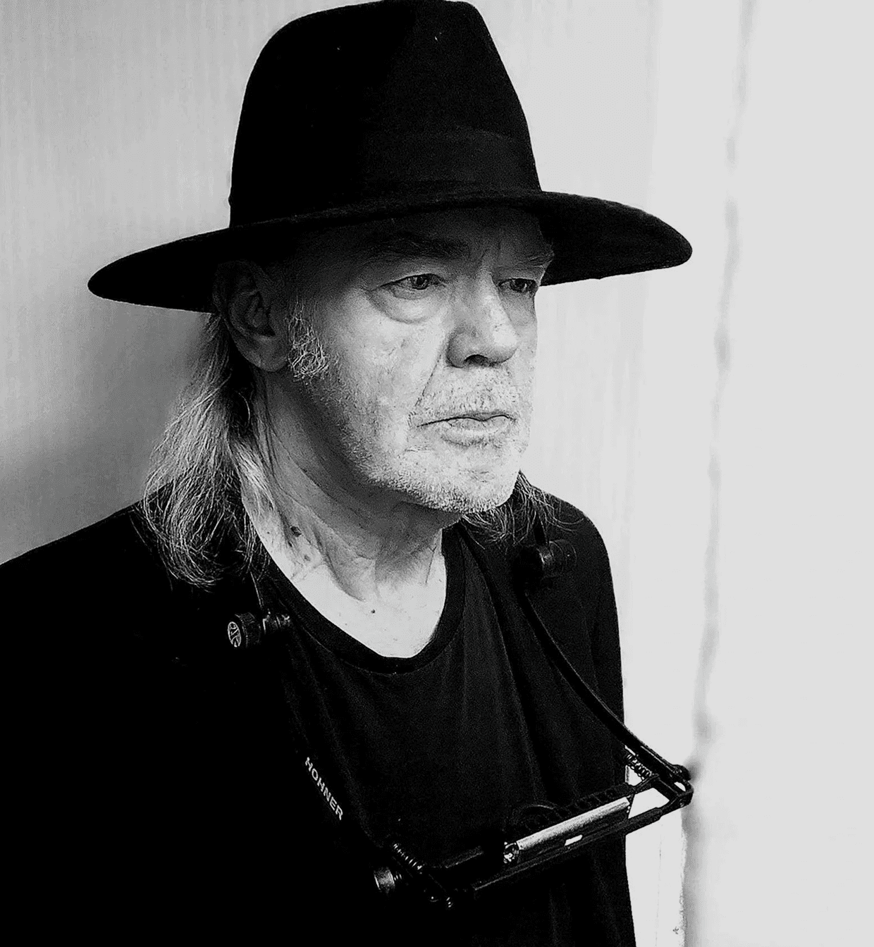 Elderly man in black hat, serious expression.